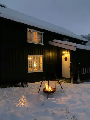 a fire pit in the snow in front of a house at Historic Log House At The Foot Of Middagstind in Sæbø
