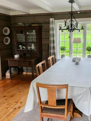 a dining room with a large white table and chairs at Historic Log House At The Foot Of Middagstind in Sæbø