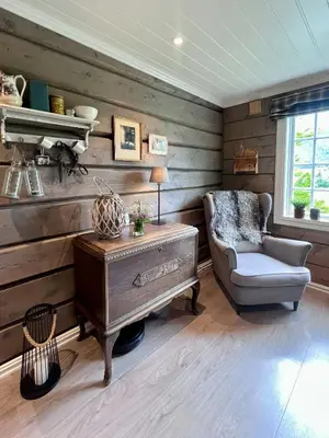 a living room with a chair and a table at Historic Log House At The Foot Of Middagstind in Sæbø