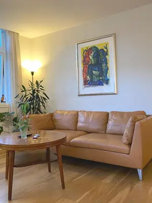 a living room with a brown couch and a table at Unique relaxed corner flat in central Bergen in Bergen