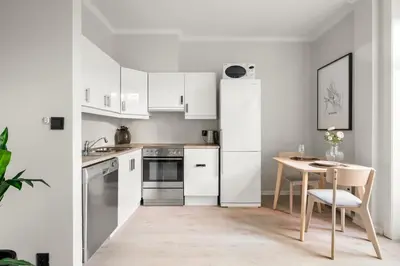 a kitchen with white appliances and a table with a chair at Bergen Beds Apartments - Unbeatable location! in Bergen