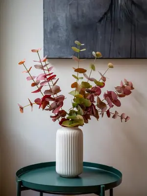 a white vase with flowers in it on a table at Authentic Bergen Apartment in Bergen