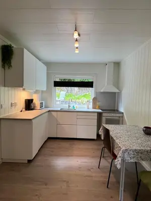 a kitchen with white cabinets and a table and a window at Green apartment in Odda