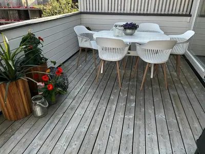 a table and chairs on a wooden deck with flowers at Lade - Aqua Nor 2025 - inntil 7 personer in Lii