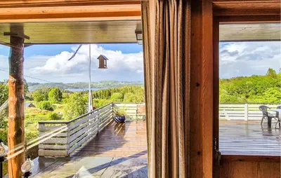 an open door to a deck with a view of the mountains at Amazing Home In Frekhaug in Frekhaug