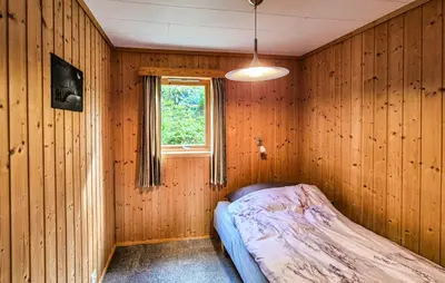 a bedroom with a bed in a wooden wall at Amazing Home In Frekhaug in Frekhaug