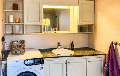 a bathroom with a sink and a washing machine at 3 Bedroom Amazing Home In Elnesvågen in Sylte
