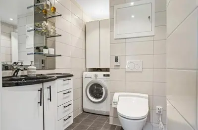 a white bathroom with a washing machine and a sink at Downtown apartment with a view in Bergen
