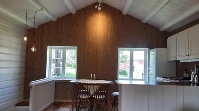 a kitchen with a table and two windows at Trivelig Stabbur på Lånke Gård