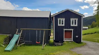 a black house with a slide and a playground at Trivelig Stabbur på Lånke Gård