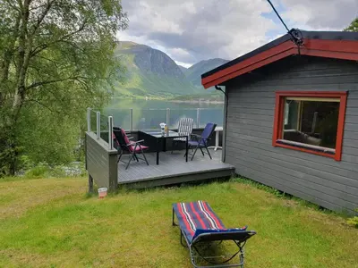 a house with a deck with a table and chairs at Feriehus Rodal med Båt in Rodal