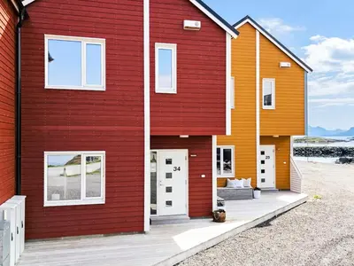 a red and orange house with a white door at 8 person holiday home in Sandøy in Finnøy