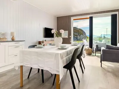 a dining room with a table with a vase of flowers at 8 person holiday home in Sandøy in Finnøy