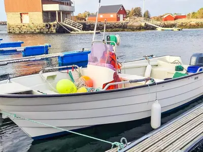 a white boat tied to a dock in the water at 8 person holiday home in Sandøy in Finnøy