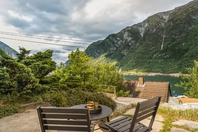 a patio with a table and two chairs and a lake at Trolltunga Fjord Stay in Odda