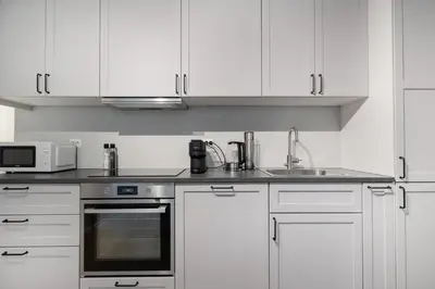 a kitchen with white cabinets and a sink and a microwave at Central stay apartment - 201 in Bergen