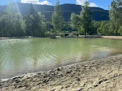 a body of water with trees and mountains in the background at Family house near Kvitfjell & Hunderfossen in Fåvang