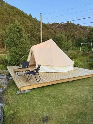 a tent with a table and a chair on a wooden deck at Ocean Glamping