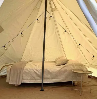 a bed in a canvas tent with a table at Ocean Glamping