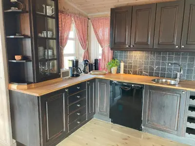 a kitchen with wooden cabinets and a black dishwasher at 10 person holiday home in NORDTORPA in Nord Torpa