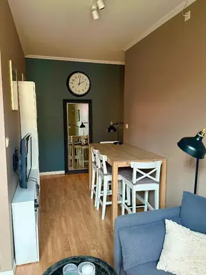 a living room with a table and a clock on the wall at Koselig bygårdsleilighet i Bergen sentrum in Bergen