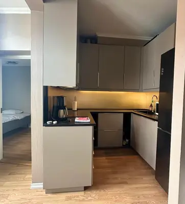 a small kitchen with white cabinets and a bed at Koselig bygårdsleilighet i Bergen sentrum in Bergen