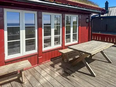 a picnic table and benches on the deck of a building at Modern Cabin With Views In Lygna in Jaren