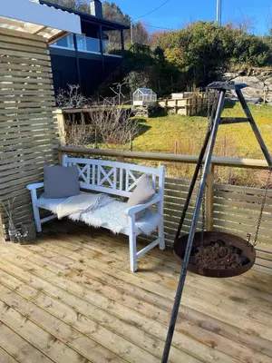 a porch with a bench and a fire pit at Koselig hytte nær sandstrand in Langenes