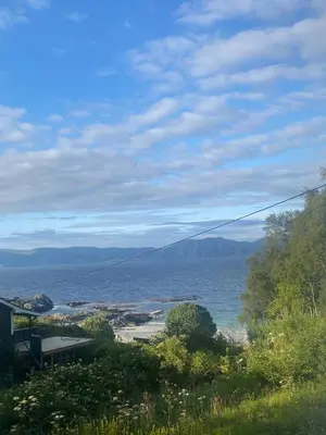 a view of a body of water with a house at Koselig hytte nær sandstrand in Langenes