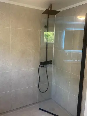 a shower with a shower head in a bathroom at Koselig hytte nær sandstrand in Langenes