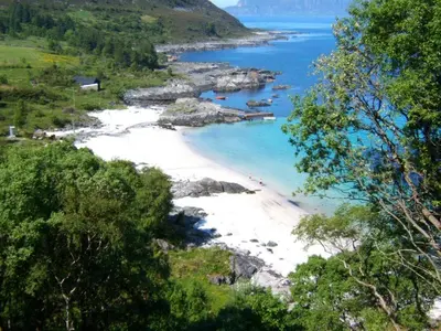 a view of a beach with people in the water at Koselig hytte nær sandstrand in Langenes