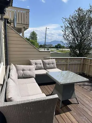 a patio with a table and wicker chairs and a table and a bench at Furnished apartment near Aker Solutions in Stord