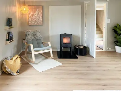a living room with a chair and a wood stove at Hyggelig Gård Nær Bergen Med Spabad in Hjelmås