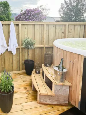 a wooden deck with a hot tub and a bench at Hyggelig Gård Nær Bergen Med Spabad in Hjelmås