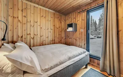 a bed in a wooden room with a window at Gaustatoppen Hytteutleie in Gaustablikk