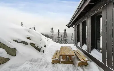 a picnic table covered in snow next to a building at Gaustatoppen Hytteutleie in Gaustablikk