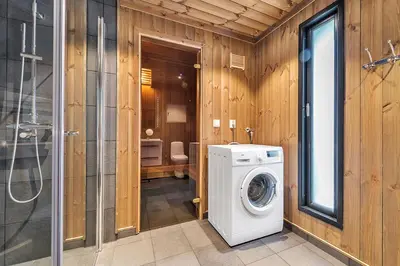 a washer and dryer in a bathroom with wooden walls at Gaustatoppen Hytteutleie in Gaustablikk