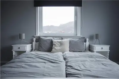 a bedroom with a bed with two night stands and a window at Location, location, location in Ervik