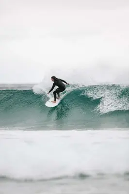 a man riding a wave on a surfboard in the ocean at Beach apartment with unique view in Ervik