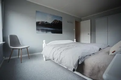 a white bedroom with a bed and a chair at Beach apartment with unique view in Ervik