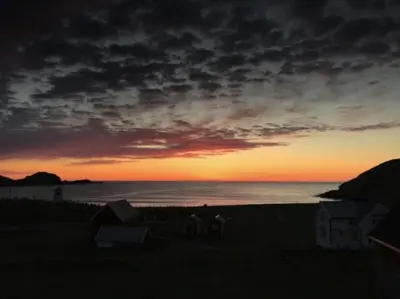 a sunset on a beach with the ocean at Location, location, location in Ervik