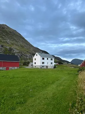 a white house in a field with a red barn at Location, location, location in Ervik