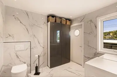 a bathroom with a shower and a toilet and a window at Lille Luxury moderne feriehus med stor uteplass, utekjøkken og pergola in Bergen