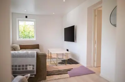 a living room with a couch and a table at Lille Luxury moderne feriehus med stor uteplass, utekjøkken og pergola in Bergen