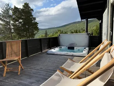 a deck with chairs and a hot tub on a house at No 105 Kongelberget in Bjorli