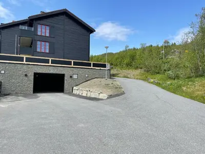 a black building with a garage and a driveway at Nice And Central With Terrace in Beitostøl