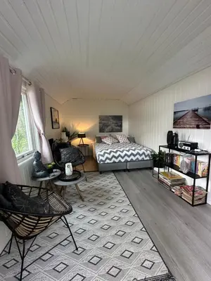 a bedroom with a bed and a table and chairs at Koselig hytte i sjøkanten in Ålesund