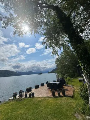 a table and chairs sitting on a wooden deck next to a lake at Koselig hytte i sjøkanten in Ålesund