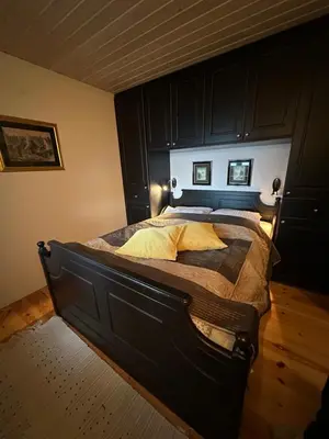 a bedroom with a large bed with a wooden headboard at Koselig hytte i sjøkanten in Ålesund