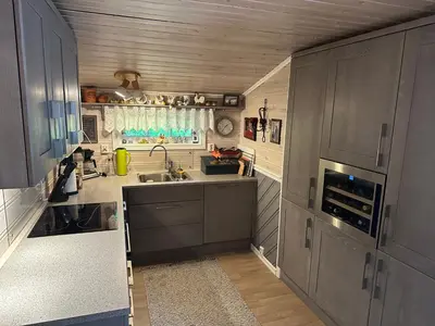 a small kitchen with gray cabinets and a sink at Koselig hytte i sjøkanten in Ålesund